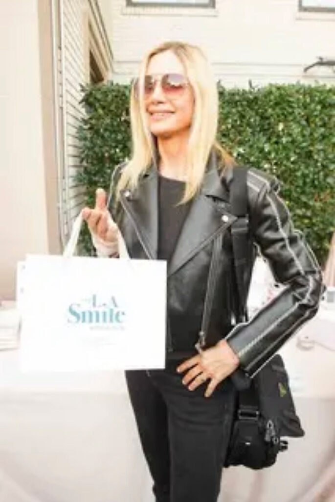 Mira Sorvino holding an LA Smile bag