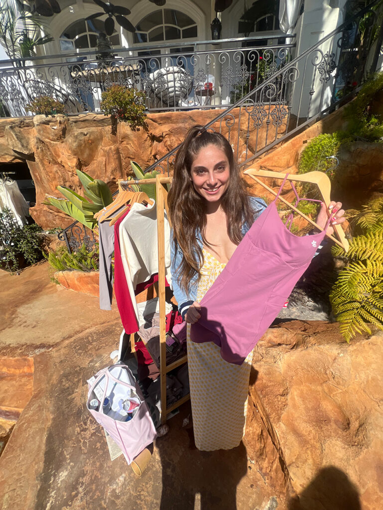 Woman holding up various outfits at Clean Living Bel Air event