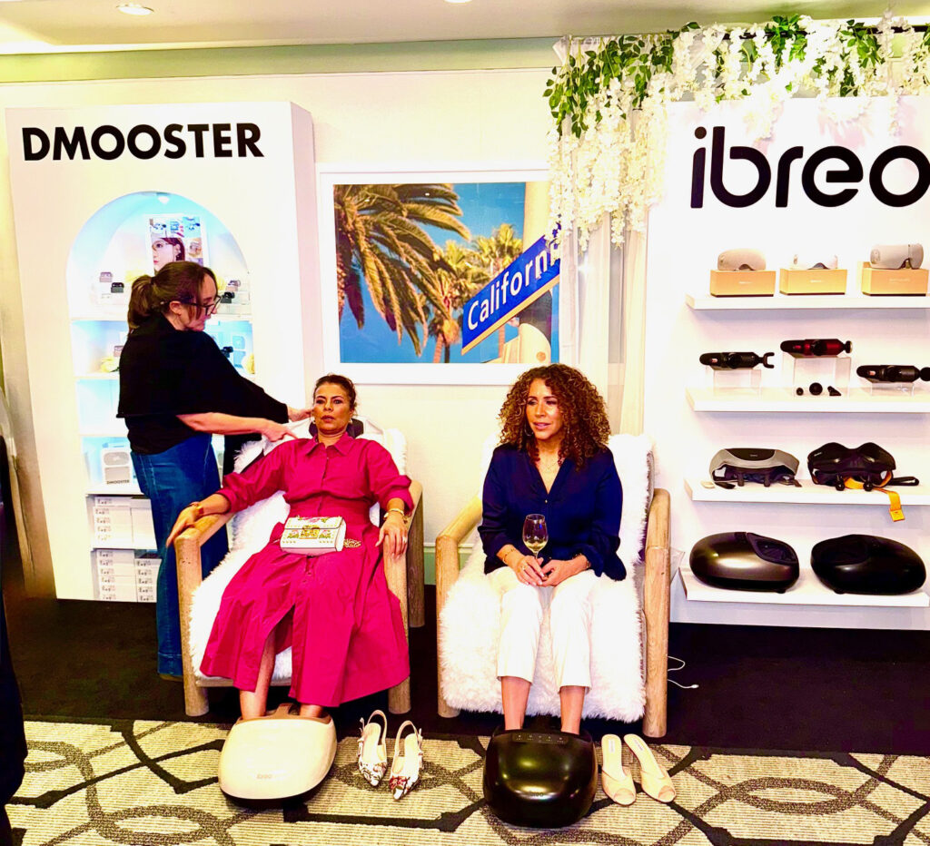 Two people getting foot massages at iBreo booth with Dmooster booth in background