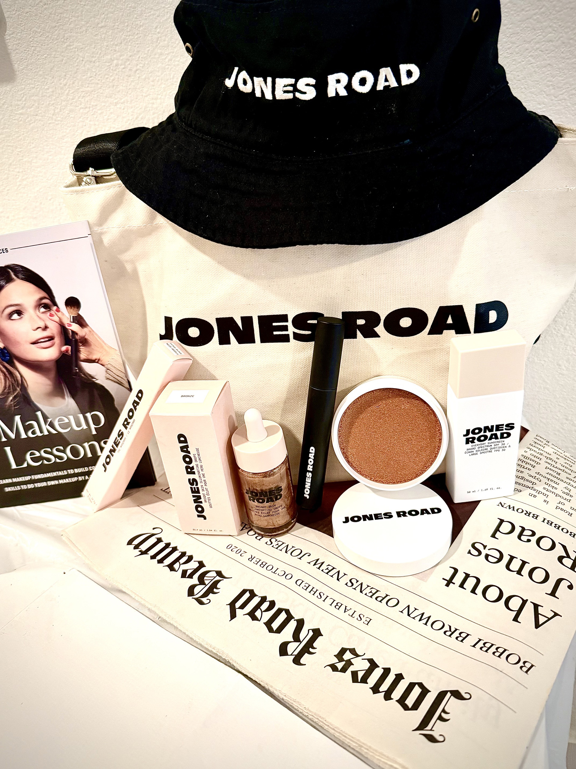 Jones Road gift bag featuring Mini Tote, Sun Hat Sunscreen, Miracle Shade, Mascara & Bright Skin Illuminating Drops Bronze