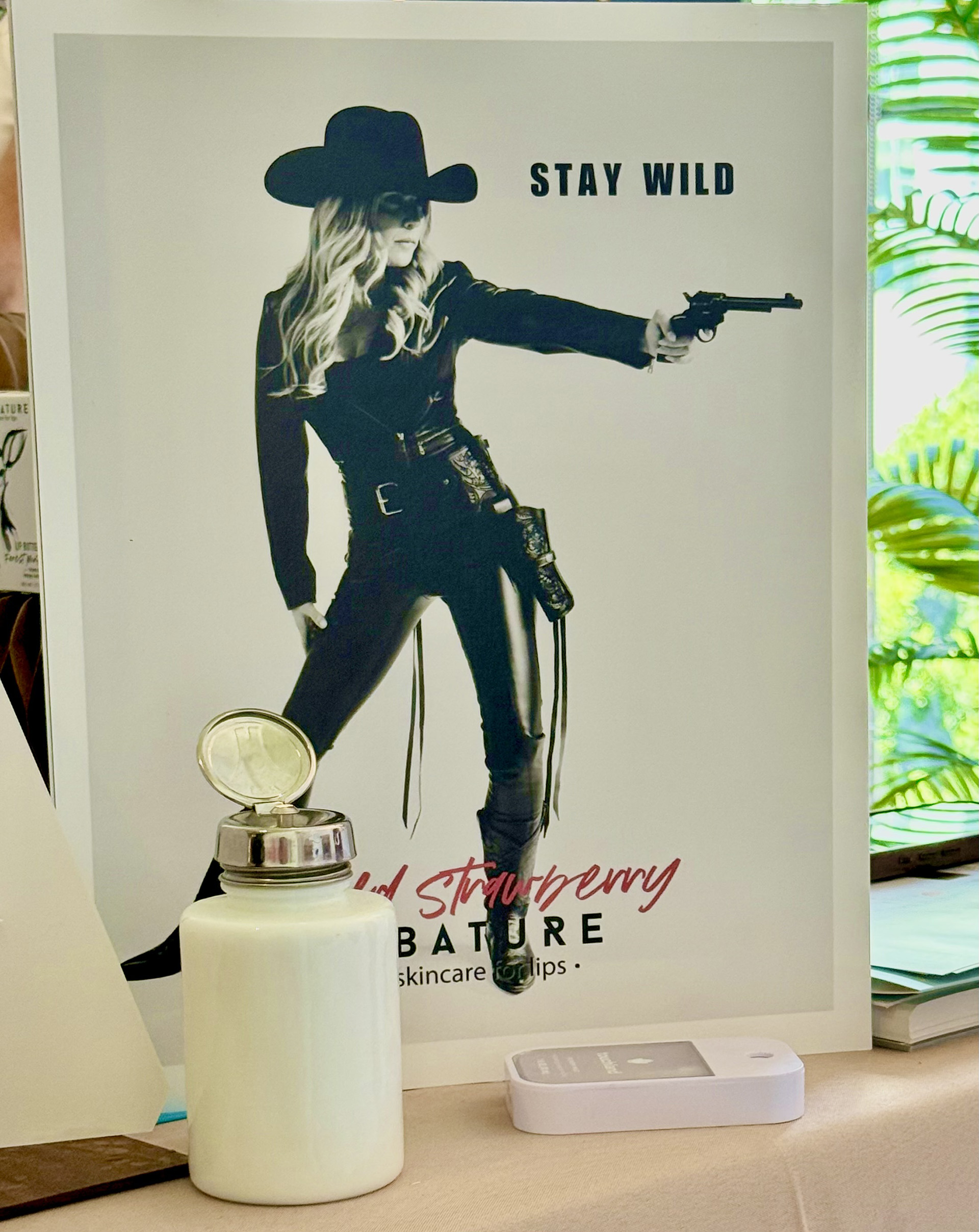 Stay Wild Sign with woman in wild west gear holding a gun saying Stay Wild at the Abature booth at Live Love Spa LA 2025