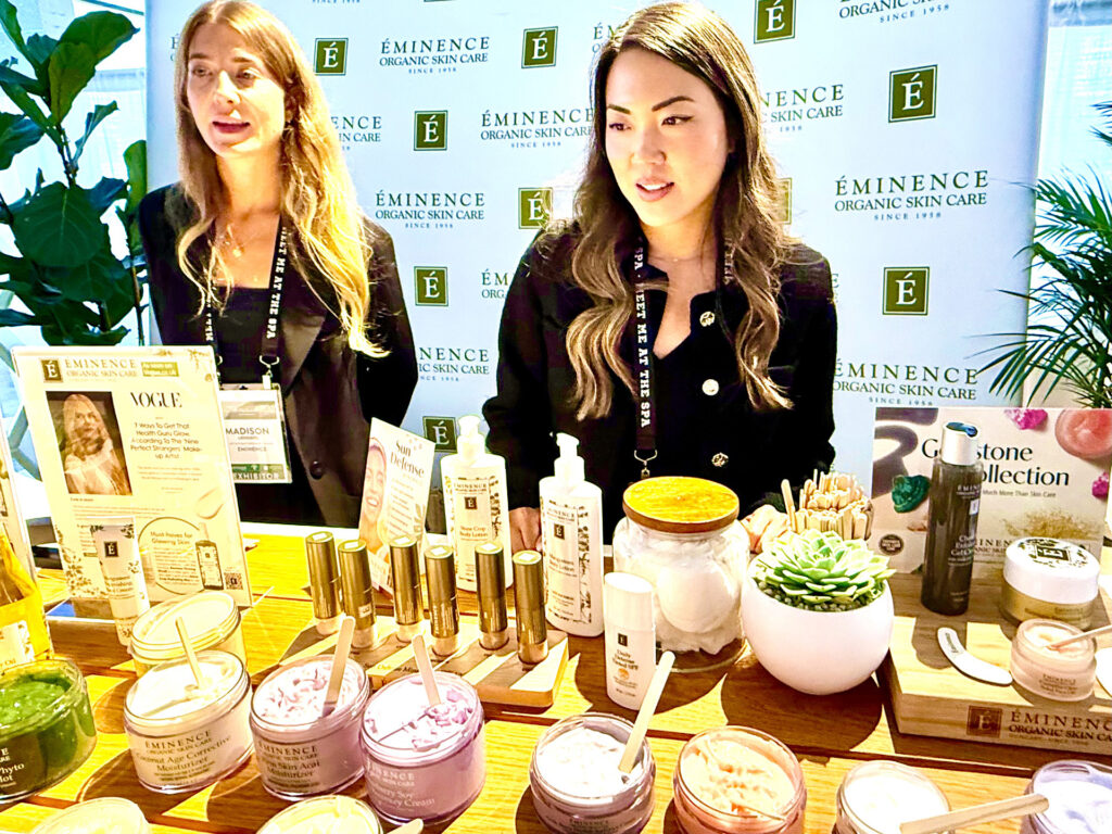 Madison and another staff member with a variety of products at the Eminence Organic Skin Care since 1938 booth