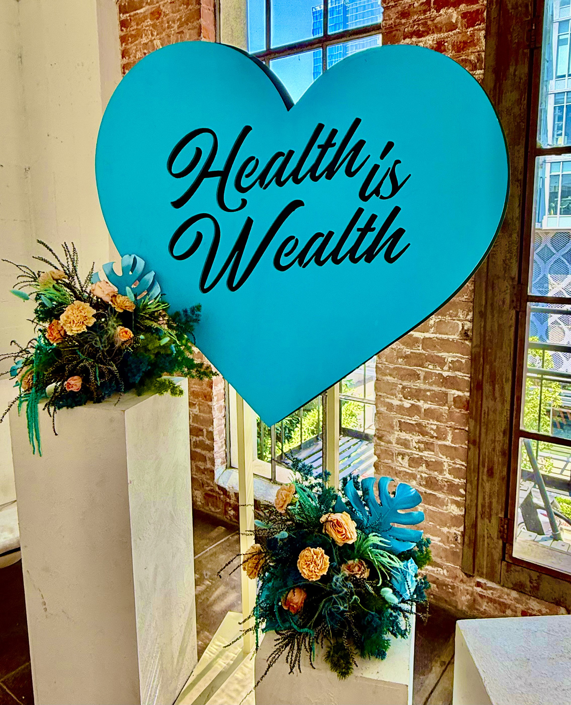 Health is Wealth inside of a blue heart with two floral bouquets
