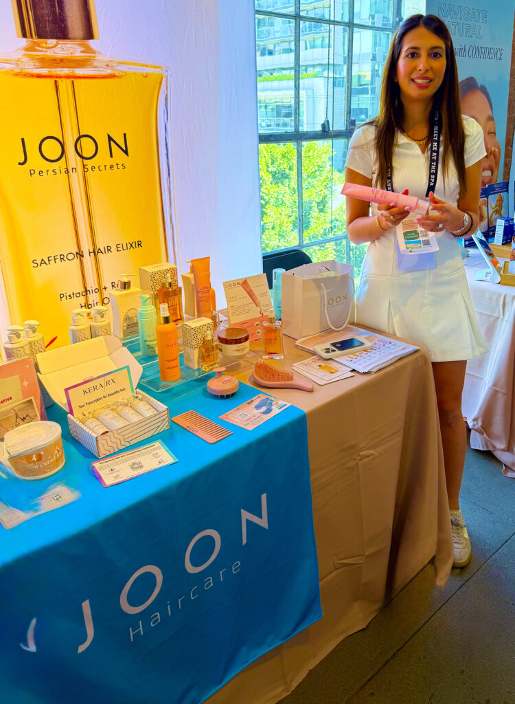 Woman standing holding a bottle of Scalp Serum at the Joon Haircare booth at Live Love Spa LA 2025