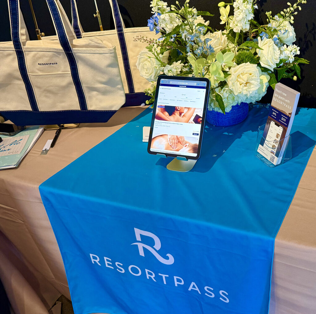 iPad with two tote bags and a floral display at the ResortPass booth at Live Love Spa LA 2025