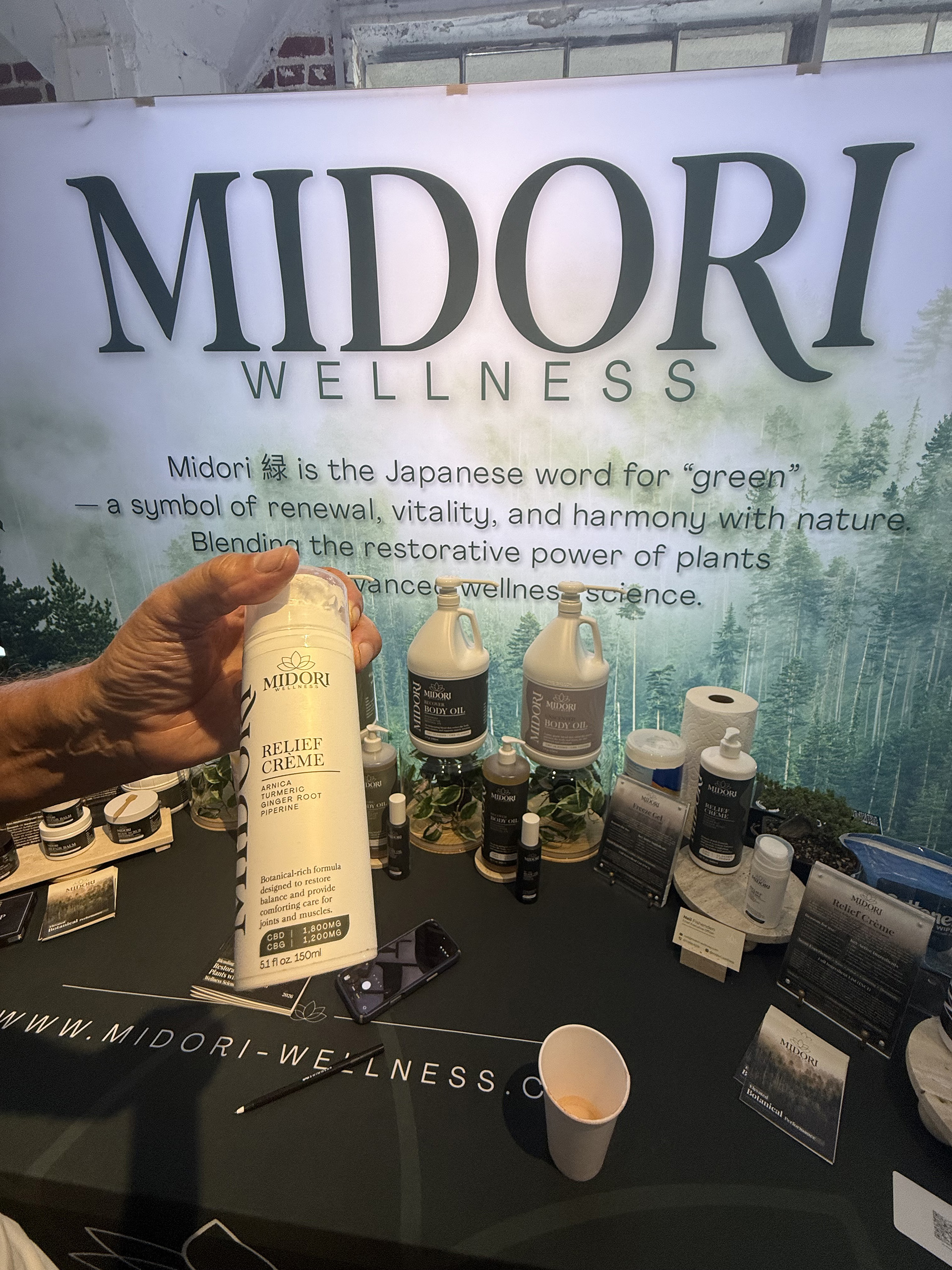 Midori Wellness Relief Creme Woman holding a bottle of Midori Wellness Relief Creme at their booth at Live Love Spa