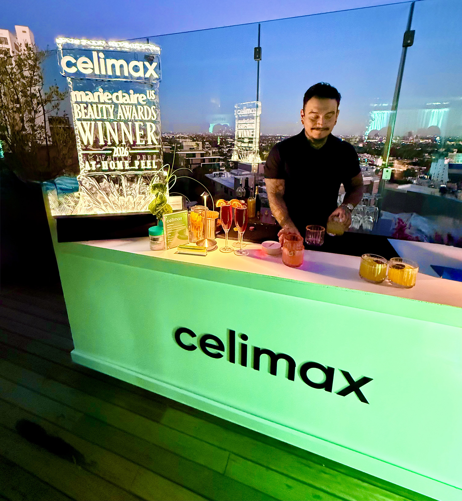 Mixologist creating drinks in front of a Marie Clarie Beauty Award ice sculpture at the Celimax bar
