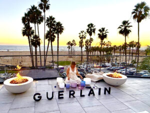 Woman performing Yoga in front of the Guerlain sign at the balcony of the Regent Santa Monica Beaches